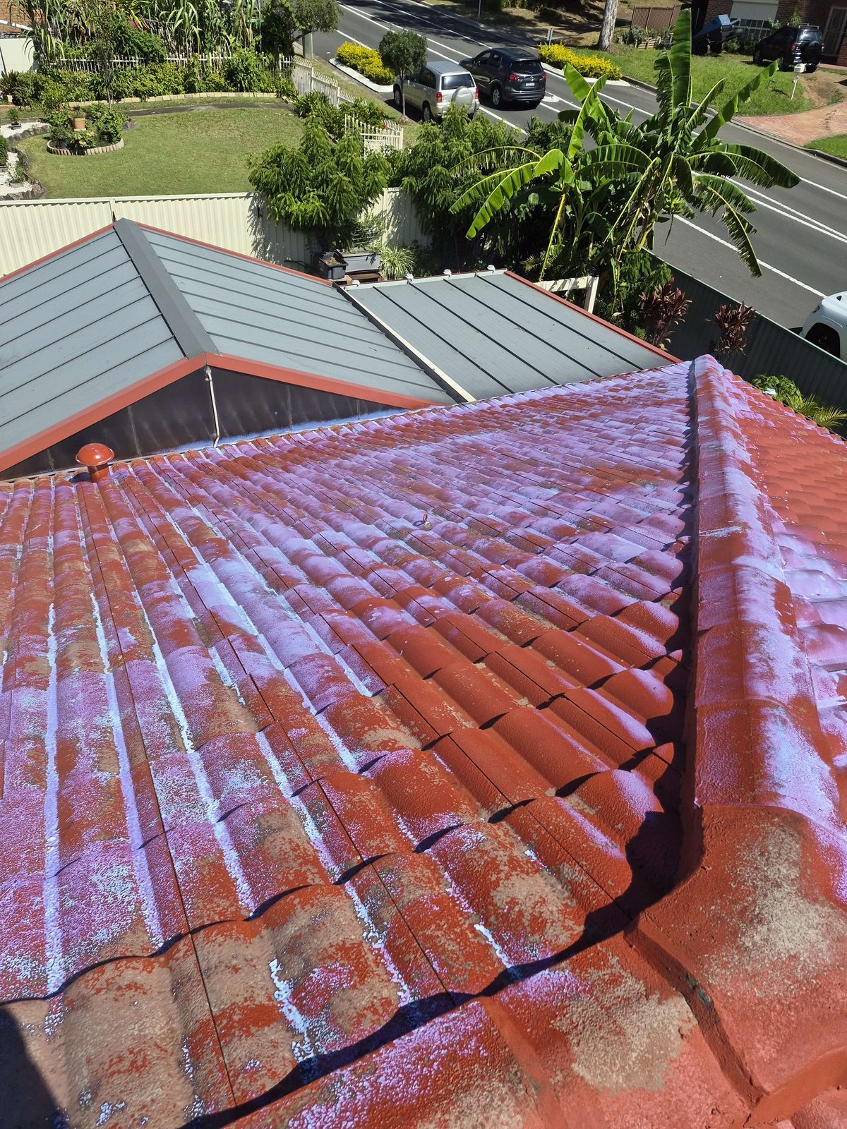 Primer coat progress on a terracotta tile roof ridge, before the colour top coat